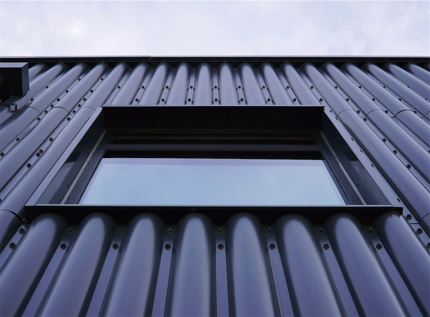Close-up of half-round profiled steel rainscreen around a window at Meopham School, made and installed by Express Facades