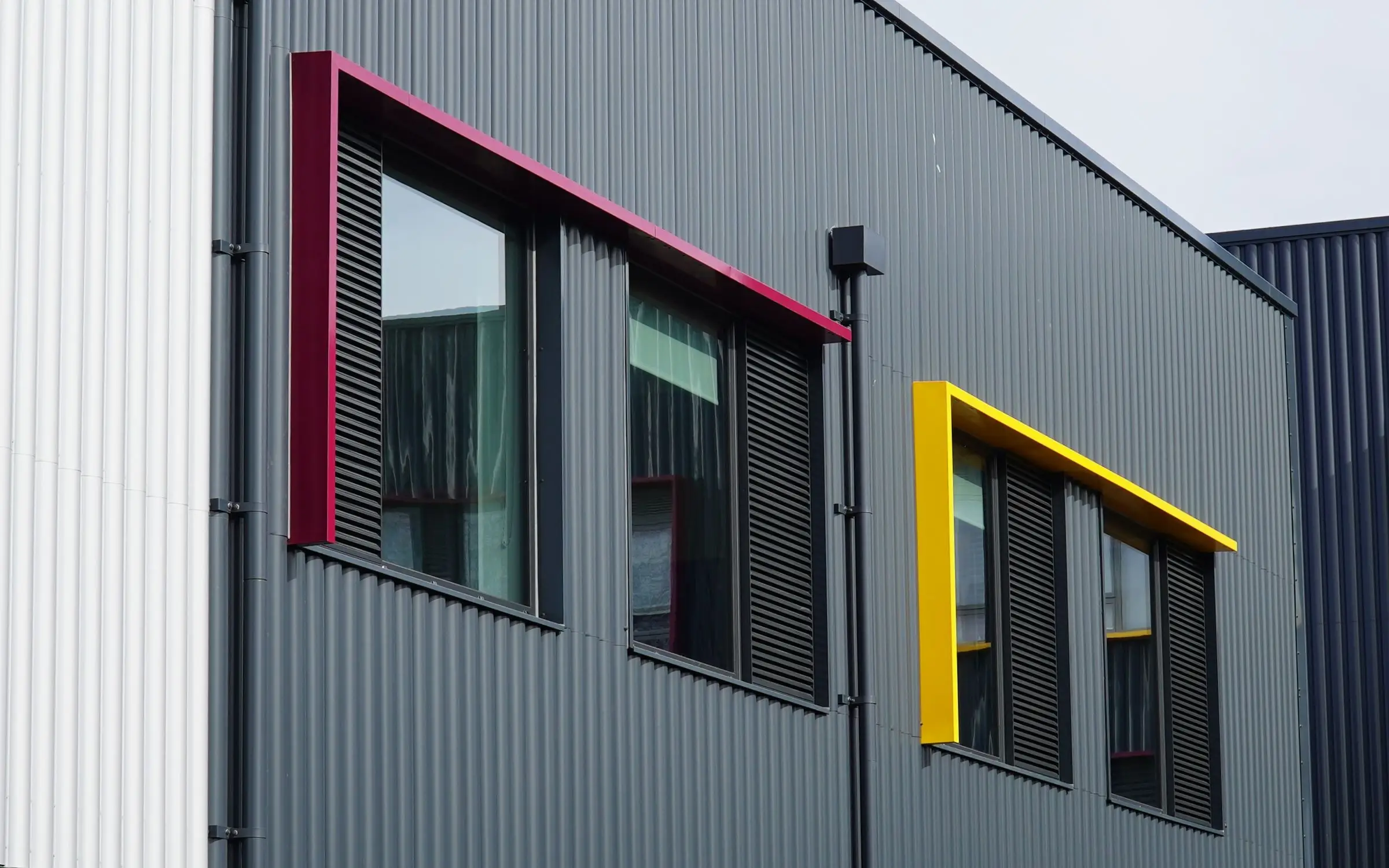 Anthracite profiled cladding at Meopham School with magenta and yellow window surrounds