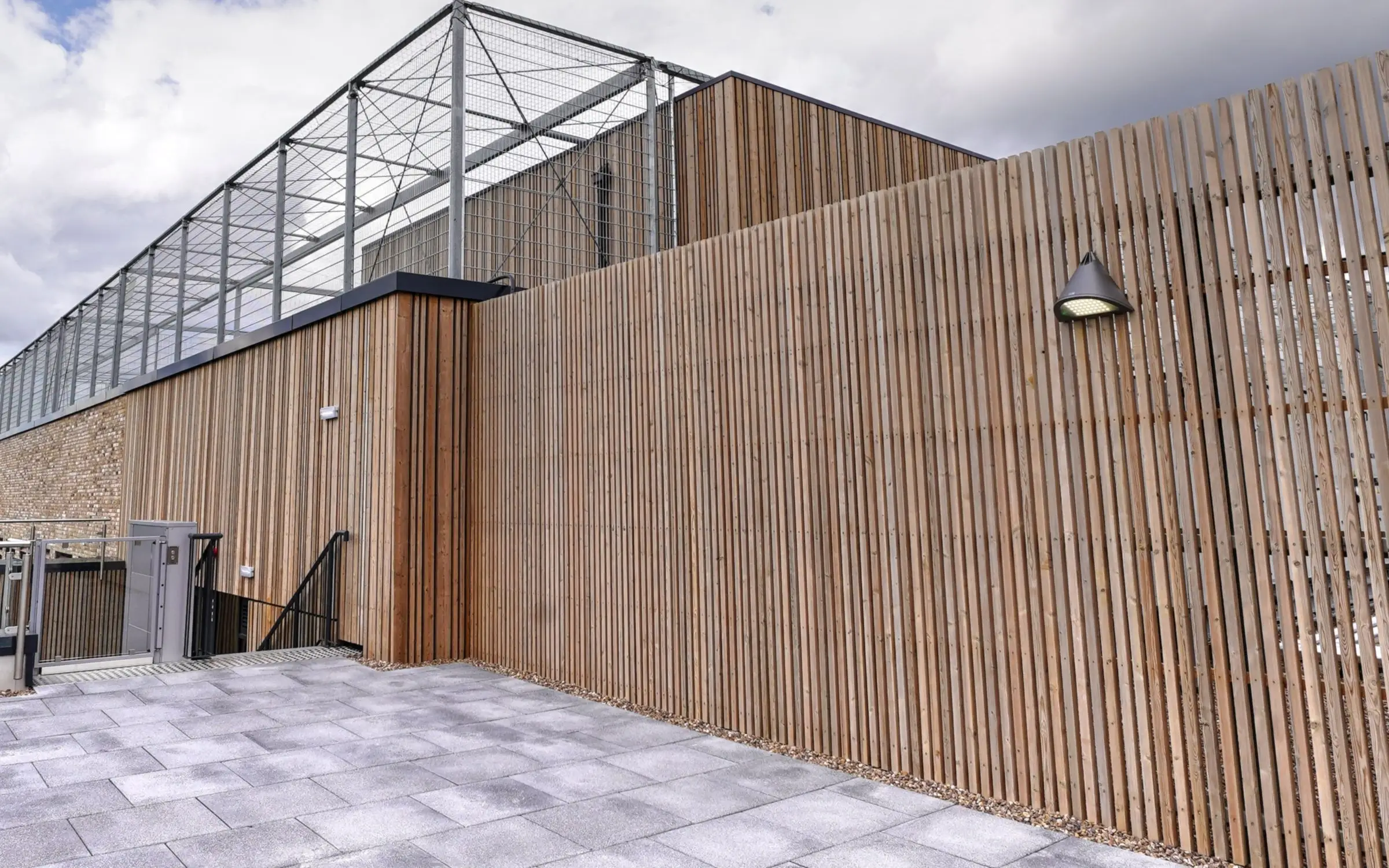Timber batten rainscreen on the roof of Spelthorne Leisure Centre, below the sports pitch enclosure