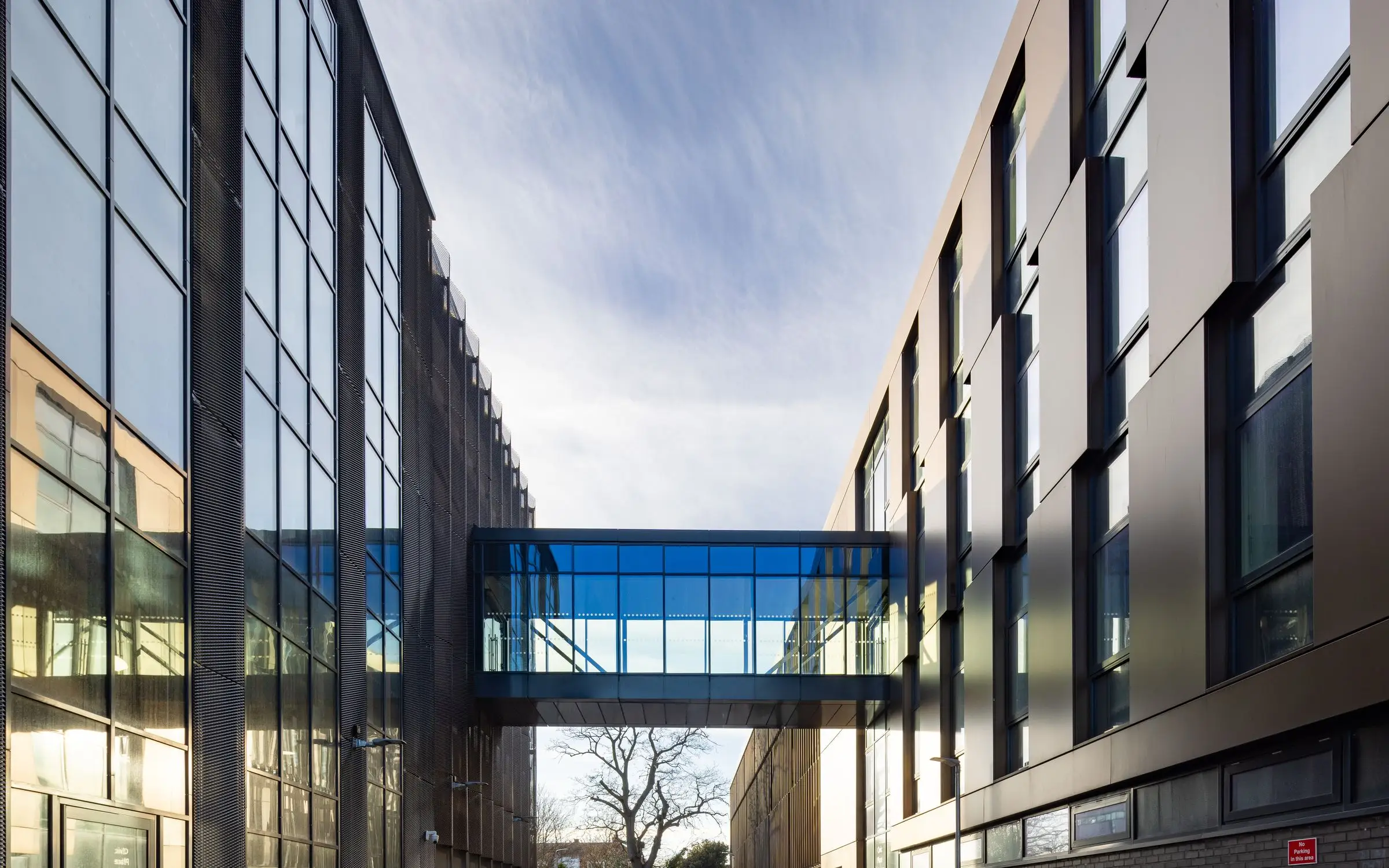 Glazed bridge crossing the street between the clad blocks of Worthing Integrated Care Centre