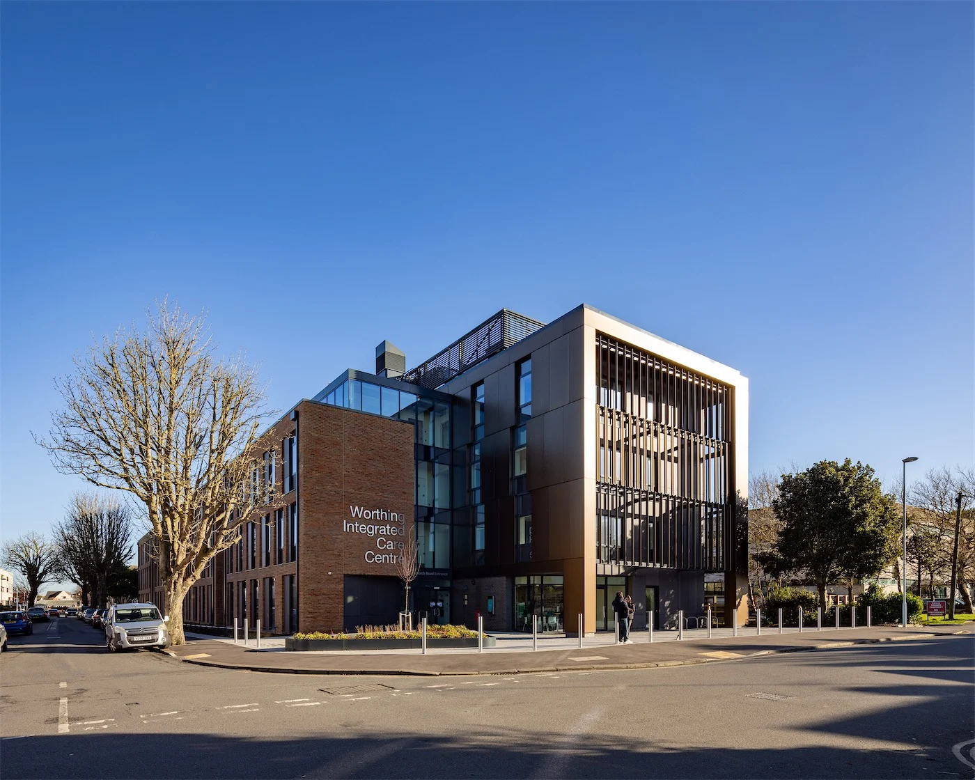 Worthing Integrated Care Centre on its street corner: bronze aluminium rainscreen panels under a blue sky